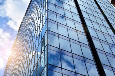 Cam aynalı ofis binasının ön dokusu. Ön cephenin bir parçası. Günbatımında akşam ışığında mercek filtre efektiyle modern gökdelenlerin en alt görüntüsü.