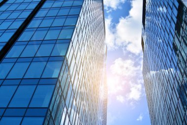 Cam aynalı ofis binasının ön dokusu. Ön cephenin bir parçası. Günbatımında akşam ışığında mercek filtre efektiyle modern gökdelenlerin en alt görüntüsü.