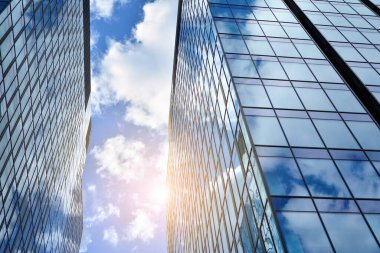 Cam aynalı ofis binasının ön dokusu. Ön cephenin bir parçası. Günbatımında akşam ışığında mercek filtre efektiyle modern gökdelenlerin en alt görüntüsü.