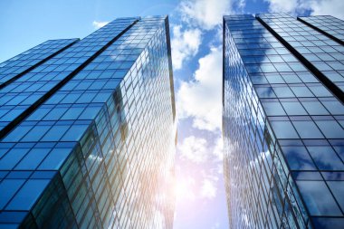 Cam aynalı ofis binasının ön dokusu. Ön cephenin bir parçası. Günbatımında akşam ışığında mercek filtre efektiyle modern gökdelenlerin en alt görüntüsü.