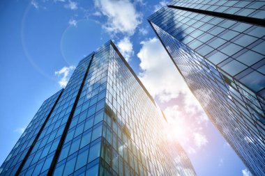 Cam aynalı ofis binasının ön dokusu. Ön cephenin bir parçası. Günbatımında akşam ışığında mercek filtre efektiyle modern gökdelenlerin en alt görüntüsü.