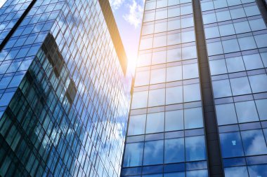 Cam aynalı ofis binasının ön dokusu. Ön cephenin bir parçası. Günbatımında akşam ışığında mercek filtre efektiyle modern gökdelenlerin en alt görüntüsü.