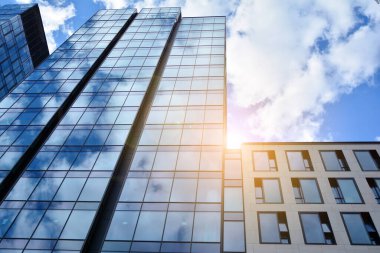 Cam aynalı ofis binasının ön dokusu. Ön cephenin bir parçası. Günbatımında akşam ışığında mercek filtre efektiyle modern gökdelenlerin en alt görüntüsü.