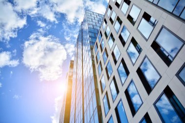 Cam aynalı ofis binasının ön dokusu. Ön cephenin bir parçası. Günbatımında akşam ışığında mercek filtre efektiyle modern gökdelenlerin en alt görüntüsü.