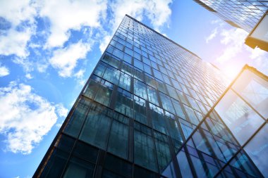 Cam aynalı ofis binasının ön dokusu. Ön cephenin bir parçası. Günbatımında akşam ışığında mercek filtre efektiyle modern gökdelenlerin en alt görüntüsü.