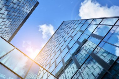 Cam aynalı ofis binasının ön dokusu. Ön cephenin bir parçası. Günbatımında akşam ışığında mercek filtre efektiyle modern gökdelenlerin en alt görüntüsü.