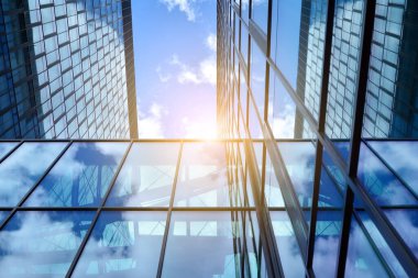 Cam aynalı ofis binasının ön dokusu. Ön cephenin bir parçası. Günbatımında akşam ışığında mercek filtre efektiyle modern gökdelenlerin en alt görüntüsü.