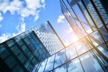 Cam aynalı ofis binasının ön dokusu. Ön cephenin bir parçası. Günbatımında akşam ışığında mercek filtre efektiyle modern gökdelenlerin en alt görüntüsü.