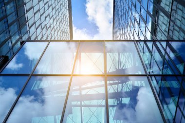 Cam aynalı ofis binasının ön dokusu. Ön cephenin bir parçası. Günbatımında akşam ışığında mercek filtre efektiyle modern gökdelenlerin en alt görüntüsü.