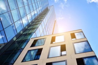 Cam aynalı ofis binasının ön dokusu. Ön cephenin bir parçası. Günbatımında akşam ışığında mercek filtre efektiyle modern gökdelenlerin en alt görüntüsü.