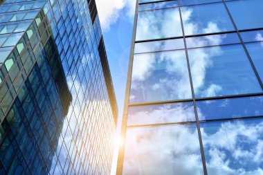 Cam aynalı ofis binasının ön dokusu. Ön cephenin bir parçası. Günbatımında akşam ışığında mercek filtre efektiyle modern gökdelenlerin en alt görüntüsü.