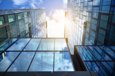 Cam aynalı ofis binasının ön dokusu. Ön cephenin bir parçası. Günbatımında akşam ışığında mercek filtre efektiyle modern gökdelenlerin en alt görüntüsü.