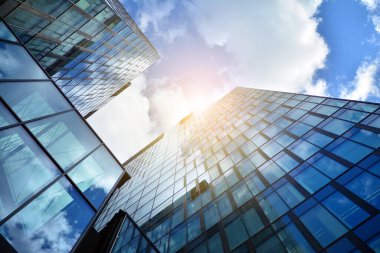 Cam aynalı ofis binasının ön dokusu. Ön cephenin bir parçası. Günbatımında akşam ışığında mercek filtre efektiyle modern gökdelenlerin en alt görüntüsü.