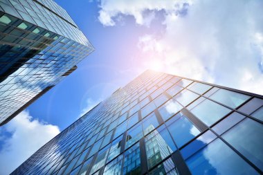Cam aynalı ofis binasının ön dokusu. Ön cephenin bir parçası. Günbatımında akşam ışığında mercek filtre efektiyle modern gökdelenlerin en alt görüntüsü.