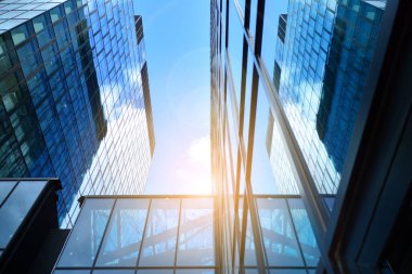Cam aynalı ofis binasının ön dokusu. Ön cephenin bir parçası. Günbatımında akşam ışığında mercek filtre efektiyle modern gökdelenlerin en alt görüntüsü.