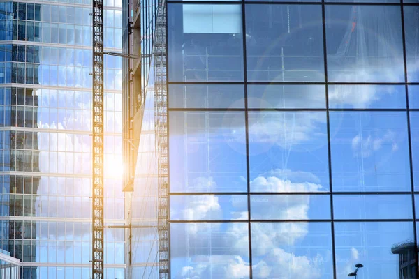 Cam aynalı ofis binasının ön dokusu. Ön cephenin bir parçası. Günbatımında akşam ışığında mercek filtre efektiyle modern gökdelenlerin en alt görüntüsü.