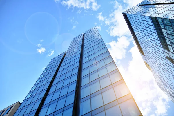 Cam aynalı ofis binasının ön dokusu. Ön cephenin bir parçası. Günbatımında akşam ışığında mercek filtre efektiyle modern gökdelenlerin en alt görüntüsü.