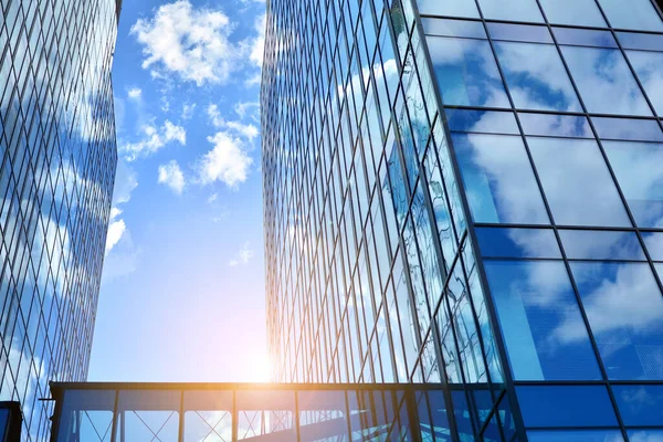 Cam aynalı ofis binasının ön dokusu. Ön cephenin bir parçası. Günbatımında akşam ışığında mercek filtre efektiyle modern gökdelenlerin en alt görüntüsü.