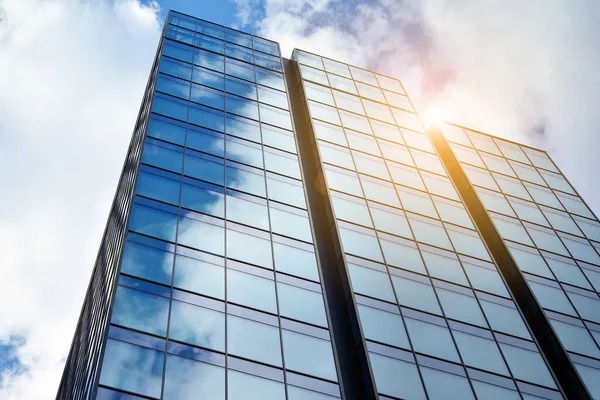 Cam aynalı ofis binasının ön dokusu. Ön cephenin bir parçası. Günbatımında akşam ışığında mercek filtre efektiyle modern gökdelenlerin en alt görüntüsü.