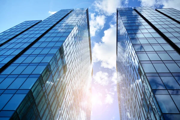 Cam aynalı ofis binasının ön dokusu. Ön cephenin bir parçası. Günbatımında akşam ışığında mercek filtre efektiyle modern gökdelenlerin en alt görüntüsü.