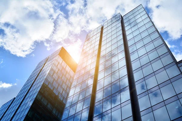 Cam aynalı ofis binasının ön dokusu. Ön cephenin bir parçası. Günbatımında akşam ışığında mercek filtre efektiyle modern gökdelenlerin en alt görüntüsü.