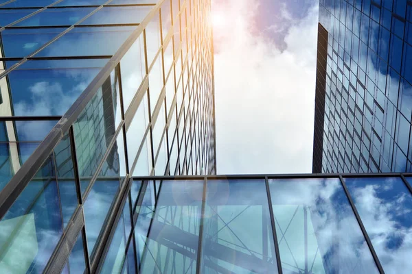 Cam aynalı ofis binasının ön dokusu. Ön cephenin bir parçası. Günbatımında akşam ışığında mercek filtre efektiyle modern gökdelenlerin en alt görüntüsü.