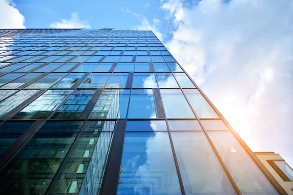 Cam aynalı ofis binasının ön dokusu. Ön cephenin bir parçası. Günbatımında akşam ışığında mercek filtre efektiyle modern gökdelenlerin en alt görüntüsü.