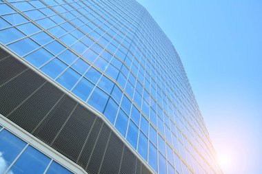 Cam aynalı ofis binasının ön dokusu. Ön cephenin bir parçası. Günbatımında akşam ışığında mercek filtre efektiyle modern gökdelenlerin en alt görüntüsü.