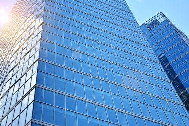 Cam aynalı ofis binasının ön dokusu. Ön cephenin bir parçası. Günbatımında akşam ışığında mercek filtre efektiyle modern gökdelenlerin en alt görüntüsü.