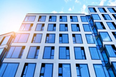 Cam aynalı ofis binasının ön dokusu. Ön cephenin bir parçası. Günbatımında akşam ışığında mercek filtre efektiyle modern gökdelenlerin en alt görüntüsü.