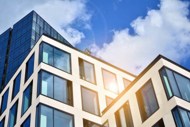 Cam aynalı ofis binasının ön dokusu. Ön cephenin bir parçası. Günbatımında akşam ışığında mercek filtre efektiyle modern gökdelenlerin en alt görüntüsü.