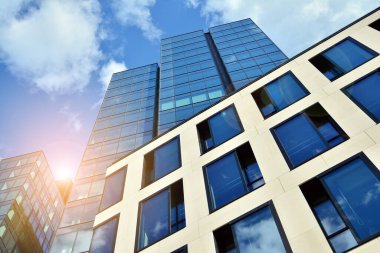 Cam aynalı ofis binasının ön dokusu. Ön cephenin bir parçası. Günbatımında akşam ışığında mercek filtre efektiyle modern gökdelenlerin en alt görüntüsü.