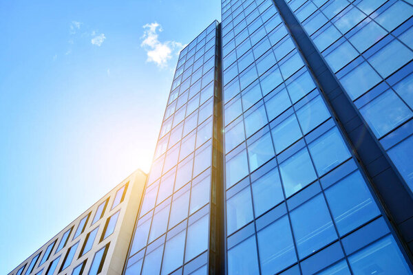 Facade texture of a glass mirrored office building. Fragment of the facade. Bottom view of modern skyscrapers in business district in evening light at sunset with lens flare filter effect.