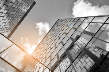 Cam aynalı ofis binasının ön dokusu. Ön cephenin bir parçası. Günbatımında güneş batımında mercek filtre efektiyle modern gökdelenlerin en alt görüntüsü. Siyah ve beyaz.