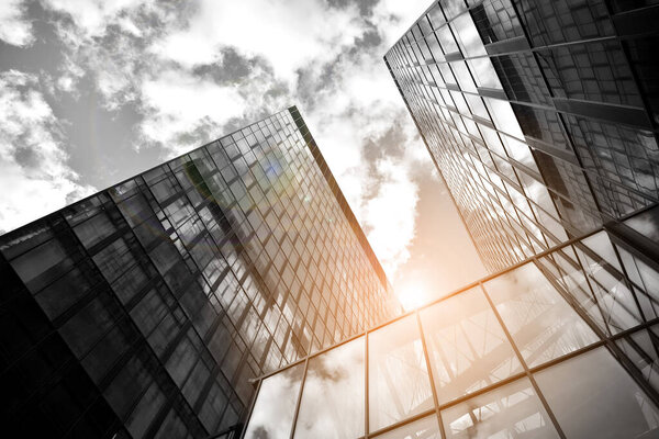 Facade texture of a glass mirrored office building. Fragment of the facade. Bottom view of modern skyscrapers in business district in evening light at sunset with lens flare filter effect. Black and white.