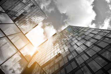 Cam aynalı ofis binasının ön dokusu. Ön cephenin bir parçası. Günbatımında güneş batımında mercek filtre efektiyle modern gökdelenlerin en alt görüntüsü. Siyah ve beyaz.