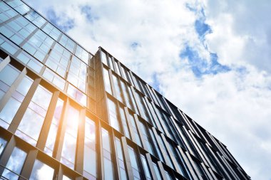 Cam aynalı ofis binasının ön dokusu. Ön cephenin bir parçası. Günbatımında akşam ışığında mercek filtre efektiyle modern gökdelenlerin en alt görüntüsü.