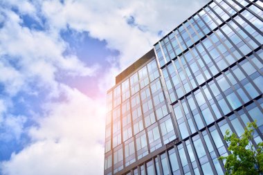 Cam aynalı ofis binasının ön dokusu. Ön cephenin bir parçası. Günbatımında akşam ışığında mercek filtre efektiyle modern gökdelenlerin en alt görüntüsü.
