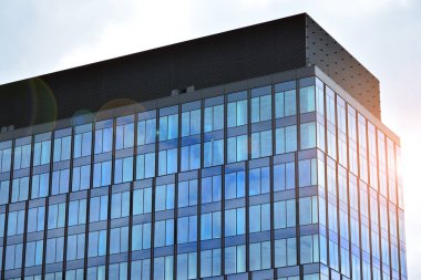 Cam aynalı ofis binasının ön dokusu. Ön cephenin bir parçası. Günbatımında akşam ışığında mercek filtre efektiyle modern gökdelenlerin en alt görüntüsü.