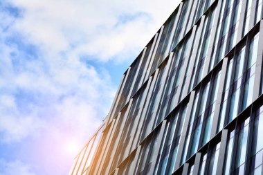 Cam aynalı ofis binasının ön dokusu. Ön cephenin bir parçası. Günbatımında akşam ışığında mercek filtre efektiyle modern gökdelenlerin en alt görüntüsü.