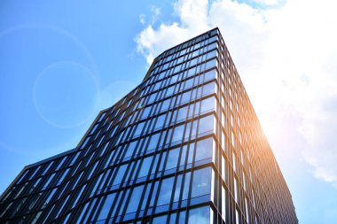 Cam aynalı ofis binasının ön dokusu. Ön cephenin bir parçası. Günbatımında akşam ışığında mercek filtre efektiyle modern gökdelenlerin en alt görüntüsü.