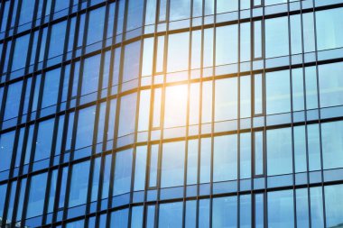 Cam aynalı ofis binasının ön dokusu. Ön cephenin bir parçası. Günbatımında akşam ışığında mercek filtre efektiyle modern gökdelenlerin en alt görüntüsü.