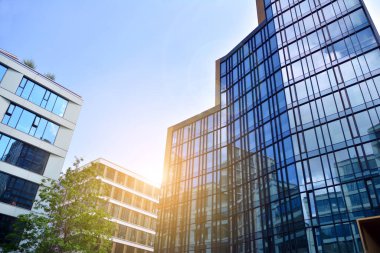 Cam aynalı ofis binasının ön dokusu. Ön cephenin bir parçası. Günbatımında akşam ışığında mercek filtre efektiyle modern gökdelenlerin en alt görüntüsü.