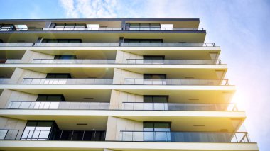 Mavi gökyüzü olan güneşli bir günde modern apartman binaları. Modern bir apartmanın ön cephesi. Güneş ışığıyla cam yüzey.