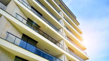 Mavi gökyüzü olan güneşli bir günde modern apartman binaları. Modern bir apartmanın ön cephesi. Güneş ışığıyla cam yüzey.