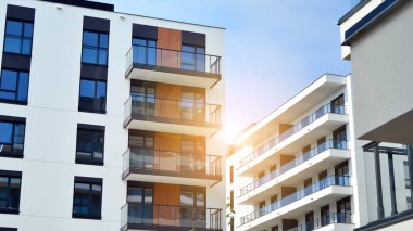 Mavi gökyüzü olan güneşli bir günde modern apartman binaları. Modern bir apartmanın ön cephesi. Güneş ışığıyla cam yüzey.