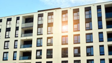 Mavi gökyüzü olan güneşli bir günde modern apartman binaları. Modern bir apartmanın ön cephesi. Güneş ışığıyla cam yüzey.