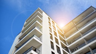 Mavi gökyüzü olan güneşli bir günde modern apartman binaları. Modern bir apartmanın ön cephesi. Güneş ışığıyla cam yüzey.