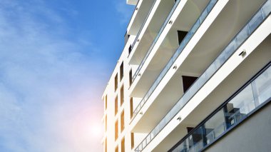 Mavi gökyüzü olan güneşli bir günde modern apartman binaları. Modern bir apartmanın ön cephesi. Güneş ışığıyla cam yüzey.