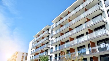 Mavi gökyüzü olan güneşli bir günde modern apartman binaları. Modern bir apartmanın ön cephesi. Güneş ışığıyla cam yüzey.